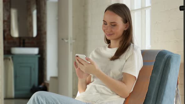 Smiling Young Woman is Resting After Work in the Free Space of the Office or at Home Sitting in an