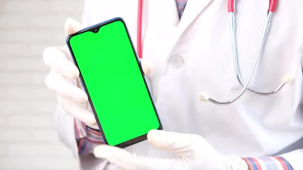 Doctor's Hand in Protective Gloves Holding Smart Phone with Green Screen