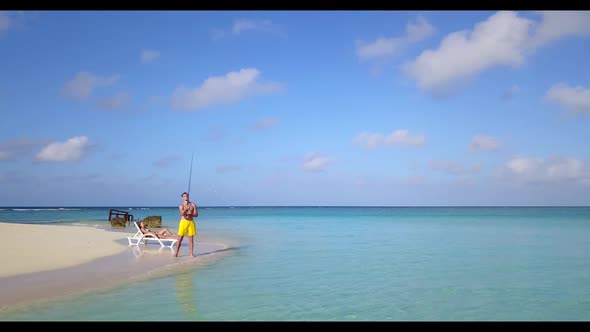 Two people happy together on exotic resort beach holiday by blue sea and white sandy background of t