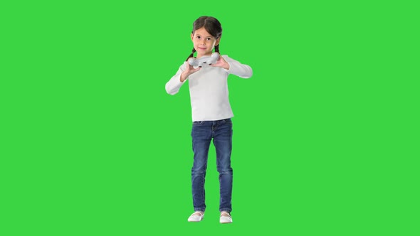 Excited Little Girl Play Videogame Holding Joystick in Her Hands on a Green Screen, Chroma Key