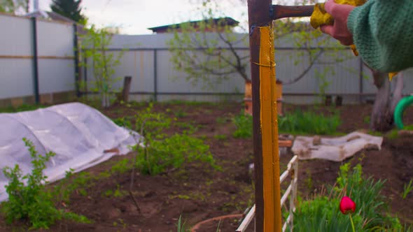 Close Up of Unrecognizable Person Paints Metal Pole with Yellow Paint on Street