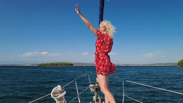 Woman Waving Hello on Bow of a Sailboat