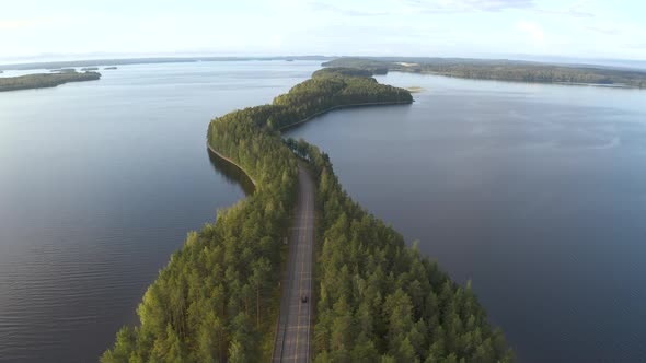 Car driving a unique road going through islands in the middle of a lake at Pulkkilanharju in Finland