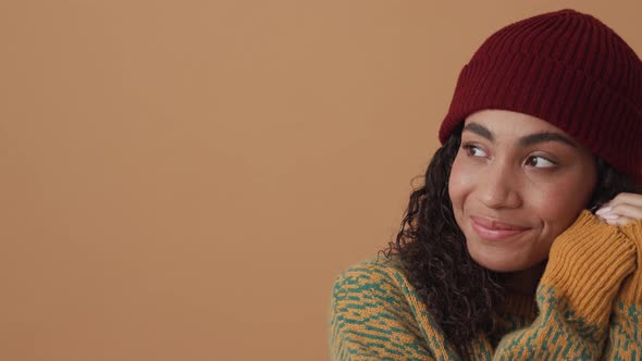 Smiling African curly-haired woman posing and looking to the side