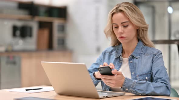Young Casual Woman Using Smartphone and Laptop at Work 