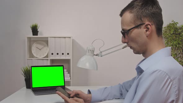 Back View of Businessman Look Green Screen Laptop in Office