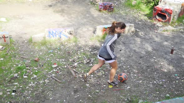 Girl dribbling soccer ball in graffiti area, athlete practicing drills alone