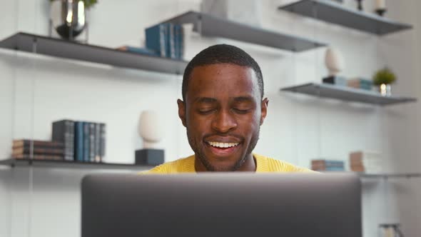 Smiling man working on laptop computer at home office. Male typing on laptop keyboard at office work