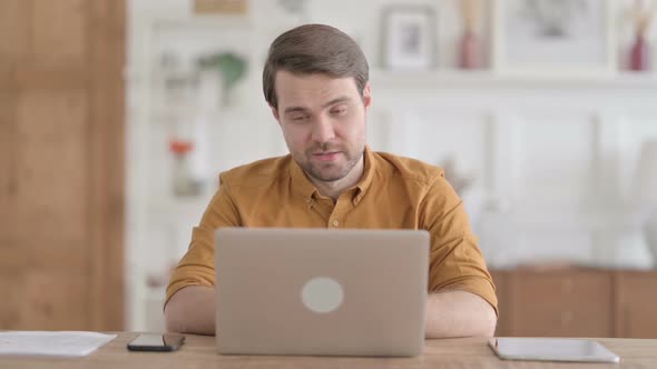 Young Man Talking on Video Call on Laptop in Office