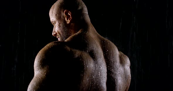 Portrait with Shoulders of a Brutal Muscular Bald Male Bodybuilder Close-up on a Black Background