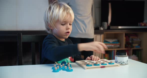 Cheerful Child Boy Playing Educational Game Sitting at the Table on Living Room