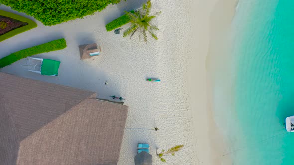 Aerial top view on young woman lies in a bikini on a surfboard on the white sand of the Maldives