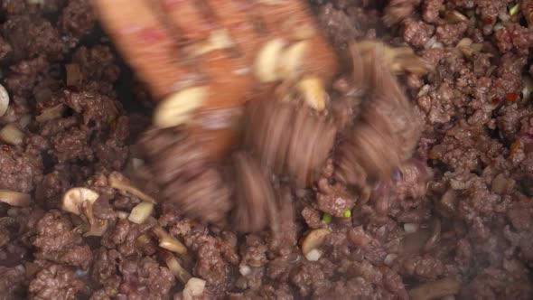 Minced Meat with Mushrooms Champignons is Fried in Frying Pan and Stirred with Wooden Spatula