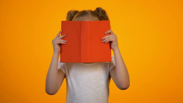 Surprised Nerd Girl in Eyeglasses Hiding Behind Book, Interesting Story, Genius