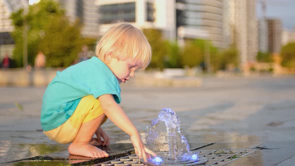 The Boy Splashes Water in the Fountain