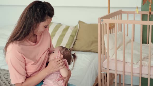 Mom Breastfeeds the Baby at Home on the Bed