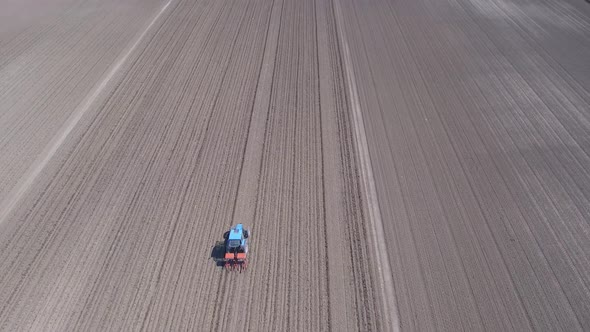 Tractor in a field ploughing, countryside aerial view