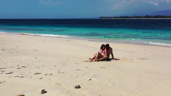 Romantic couple sunbathing on exotic seashore beach holiday by turquoise lagoon and white sandy back