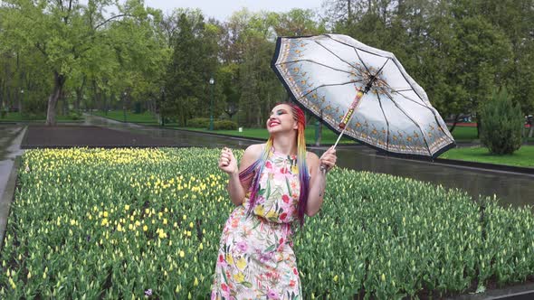 Girl with African Braids and Makeup in Spring Dress is Dancing in the Rain with Umbrella in Yellow