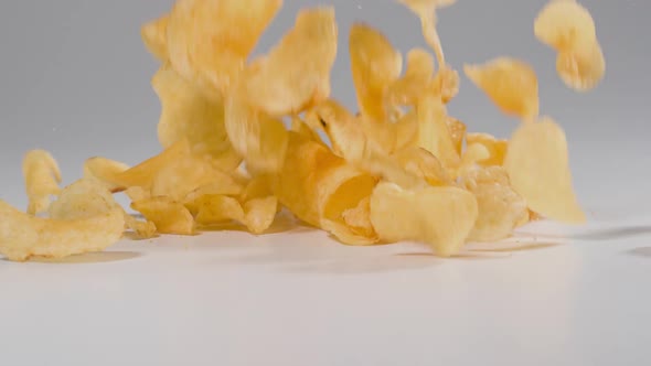 Potato Chips falling onto a white surface in slow motion