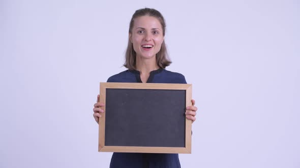 Happy Young Beautiful Businesswoman Holding Blackboard and Looking Surprised