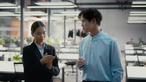 Asian Female And Male Colleagues Sanitizing Hands In Office