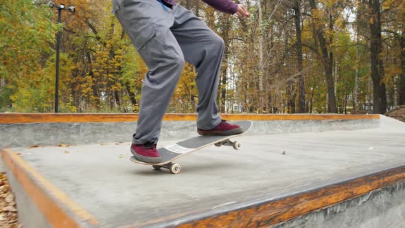 Skater Practicing in the Autumn Concrete Skate Park Making Tricks and Rides in Ramp