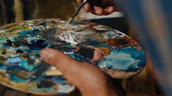 Artist Brush Mix Color Oil Painting on Palette Is Holding in His Hand Closeup