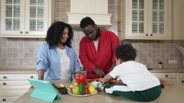 Confident African American Husband Slicing Ingredients for Healthful Salad Talking with Young Wife