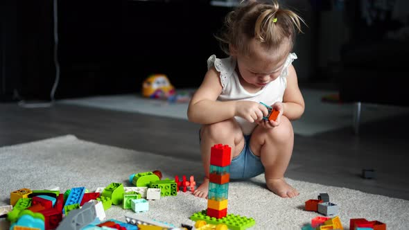 Caucasian Child a Little Girl is Playing in the Constructor at Home