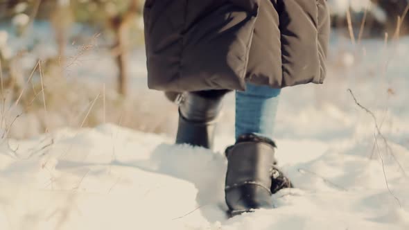 Legs Footprints In Winter Boots Walking On Snow. Female In Snowy Weather At Cold Temperature Walking