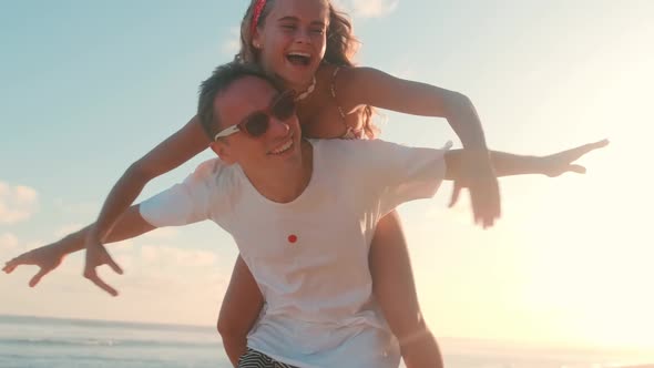 Young Joyful Energetic Caucasian Couple Having Fun on Seacoast or Beach