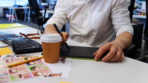 Male graphic designer working on graphic tablet at desk