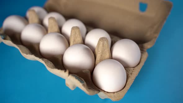 Farm Raw Fresh White Chicken Egg in an Egg Box on a Blue Background