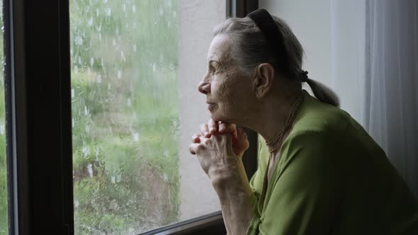 Old Woman Looks Outside the Window