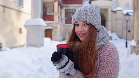 Stylish Woman Traveler with Hot Drink in Cup Looking Around Through City Street During Vacations