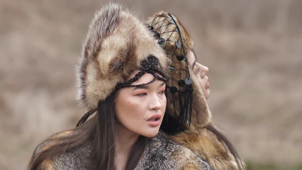 close-up two Asian young women in ethnic clothes posing in the steppe in nature. Slow motion