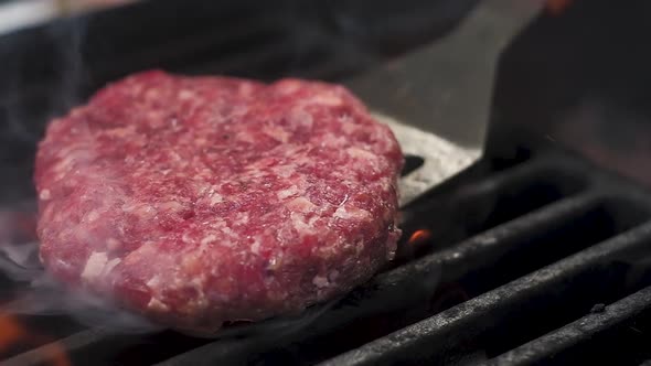 fresh meat for burgers is turned over on a hot grill. Slow motion