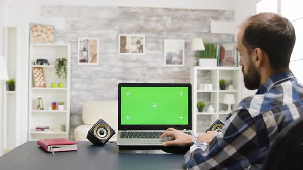 Man at the Table Browsing the Internet on Green Screen Laptop