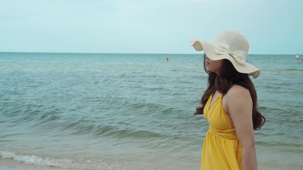 young woman in yellow dress walking on the sea beach