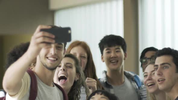 Group of students taking selfie with smart phone in corridor
