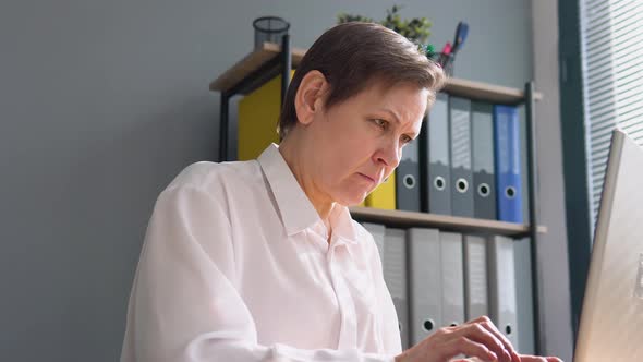 Senior Woman Works Behind a Laptop