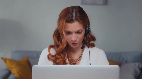 Caucasian Woman with Headset Talking and Laughing Looking Into Laptop