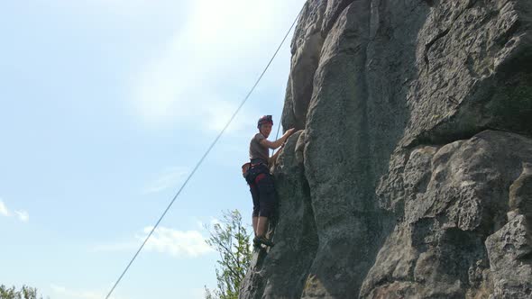 Determined Climber Clambering Up Steep Wall of Rocky Mountain