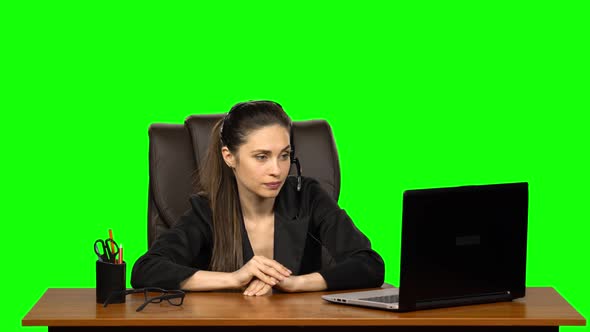 Business Woman in Headphones Speaking By Webcam and Look at Laptop. Green Screen