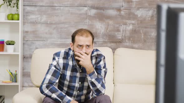 Bearded Man Sitting on Sofa with Shocked Expression