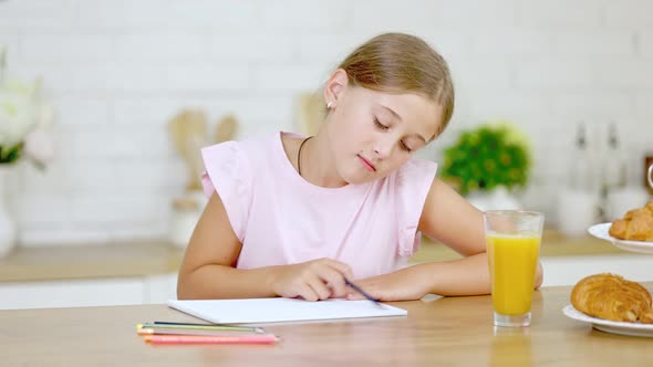 Girl Draws While Sitting in the Kitchen