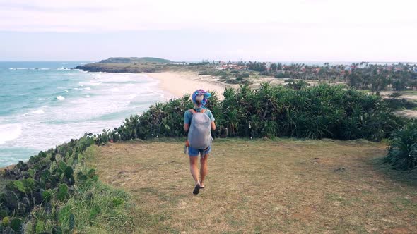 Slow motion: Woman with backpack hiking on cliff above tropical coast, Vietnam