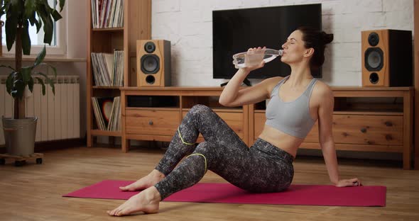 Young Woman Is Resting and Drinking Water After Exercising at Home