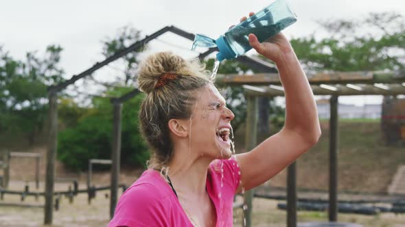 Caucasian woman pouring water on her face at bootcamp